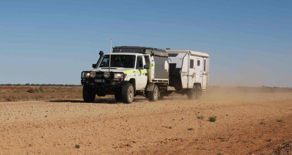 Birdsville Track with caravan travelling through gibber-covered desert landscape