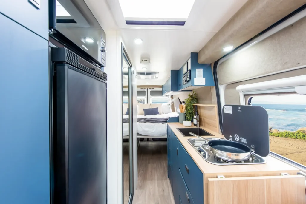 Interior of the Jayco JRV‑X campervan showing the flip‑up bed, dinette and kitchen